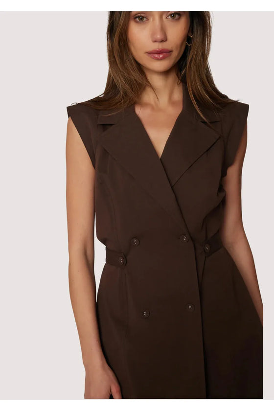 Woman wearing a brown sleeveless blazer dress on a white background