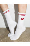 White socks with red stripes and a heart design on a neutral background