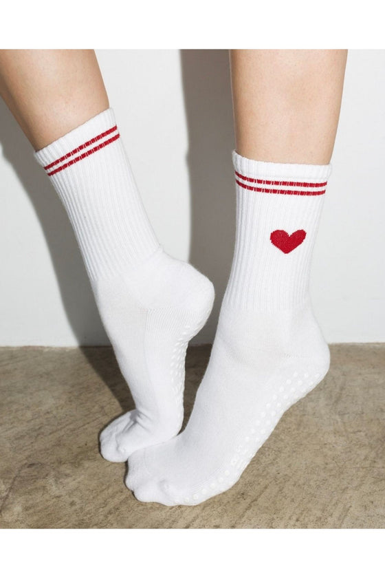 White socks with red stripes and a heart design on a neutral background