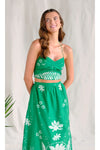 Woman wearing a green floral two piece matching set against a plain background