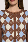 A close-up of a woman wearing a brown, cream, and light blue argyle knit cardigan sweater with brown buttons down the front.