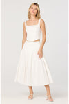 Woman wearing a white matching set with crop top and midi skirt on white background. 
