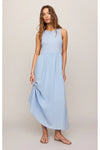 Woman wearing a light blue sleeveless midi dress with strapy sandals against a plain white background.