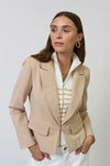 Woman wearing a beige blazer with a white and beige striped sweater insert and white pants on a plain background. 