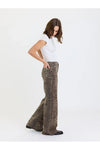 A woman modeling a pair of wide-leg pants with a brown and black leopard print pattern, paired with a white t-shirt, against a plain white studio background.