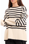 A woman wearing a cream and black horizontally striped ribbed knit sweater, cropped from the mouth down to the hips against a plain white background.