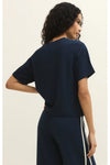 Woman shown from the back wearing a navy blue short sleeve t-shirt and matching pants against a white background. 