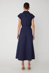 Woman shown from behind wearing a navy blue midi dress with a navy belt on a white background