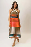 Woman wearing a multi-color striped midi dress with a halter neck on a plain background