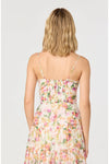 Woman shown from the back wearing a floral dress with thin straps on a plain white background. 