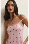 Woman wearing a pink lace-trimmed chemise with red heart patterns against a plain background. 