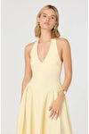Woman wearing a light yellow halter neck dress on a white background. 