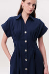 Short sleeve navy blue dress with and gold buttons on a plain white background