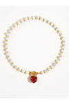 Pearl necklace with a red heart pendant on a white background. 