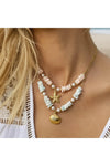 Necklace with starfish and shell charms worn by a women on a white background. 