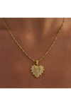 Gold necklace with a heart-shaped pendant worn on a women's neck. 