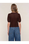 Woman wearing a brown knitted sweater and blue jeans on a beige background