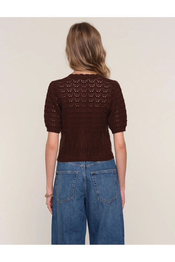 Woman wearing a brown knitted sweater and blue jeans on a beige background