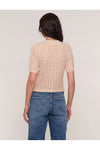 Person wearing a beige crochet top and blue jeans on a plain background