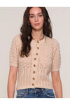 Woman wearing a beige crochet cardigan with buttons on a plain background