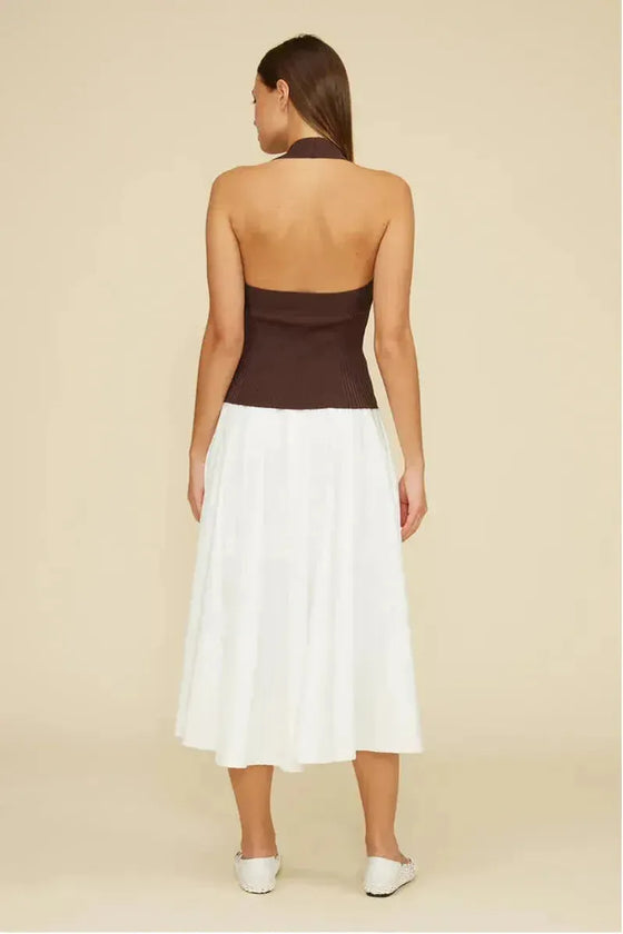 Woman wearing a two-tone dress with brown top and white skirt on a beige background